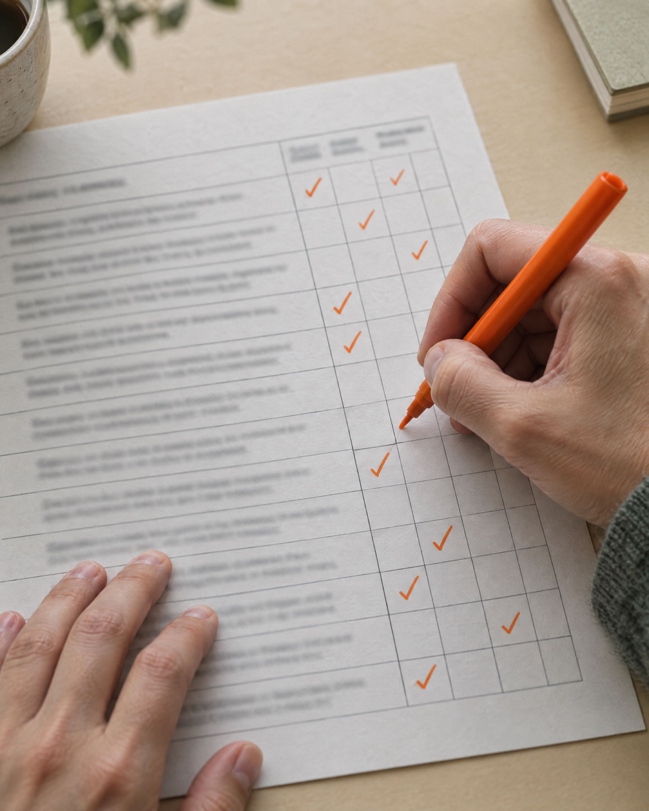 Hands marking up a printed evaluation rubric with an orange pen.